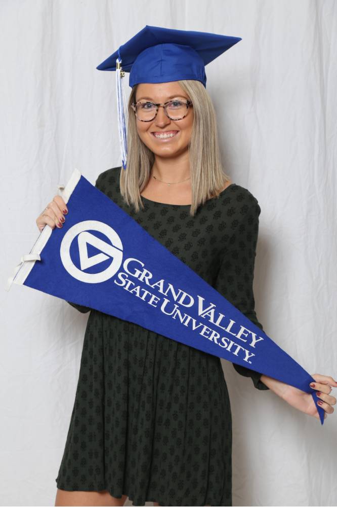 Upcoming graduate poses with the GV flag at GradFest